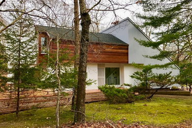 Réalisation d'une petite façade de maison blanche design en bois à un étage avec un toit à croupette.