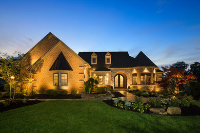 Large elegant red one-story brick house exterior photo in Cincinnati with a hip roof and a shingle roof