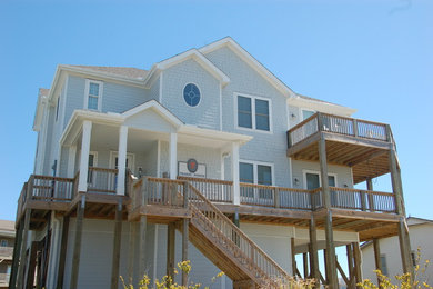 Modelo de fachada de casa gris marinera grande de tres plantas con revestimiento de madera, tejado a dos aguas y tejado de teja de madera