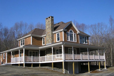 Cette photo montre une façade de maison marron chic avec un toit à quatre pans.