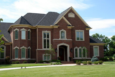 Esempio della facciata di una casa grande rossa a due piani con rivestimenti misti