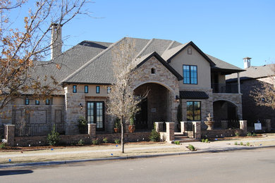 Large elegant brown two-story stone house exterior photo in Austin with a hip roof and a shingle roof
