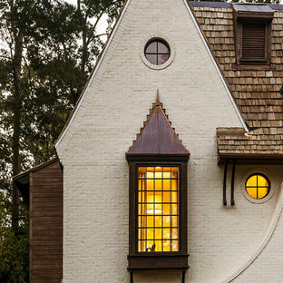 Idee per la facciata di una casa bianca classica a due piani con rivestimento in mattoni e copertura a scandole