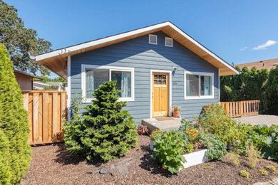 Diseño de fachada de casa azul de estilo americano de tamaño medio de una planta con revestimiento de madera y tejado a dos aguas