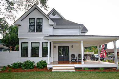 Diseño de fachada de casa blanca tradicional grande a niveles con revestimiento de madera, tejado a dos aguas y tejado de teja de madera