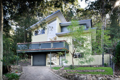 Пример оригинального дизайна: большой, трехэтажный, зеленый частный загородный дом в современном стиле с облицовкой из ЦСП, плоской крышей и металлической крышей