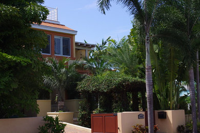 Example of a large trendy yellow two-story stucco house exterior design in Miami with a hip roof and a metal roof