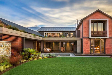 Imagen de fachada de casa contemporánea grande de dos plantas con revestimiento de ladrillo y techo verde