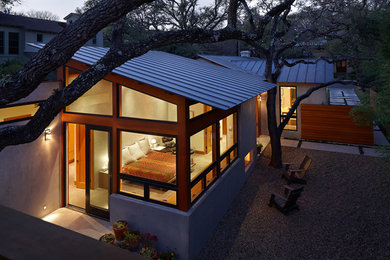 Diseño de fachada minimalista pequeña de una planta con revestimiento de estuco y tejado a dos aguas