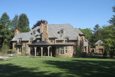 Example of a huge arts and crafts brown three-story stone exterior home design in Philadelphia with a clipped gable roof