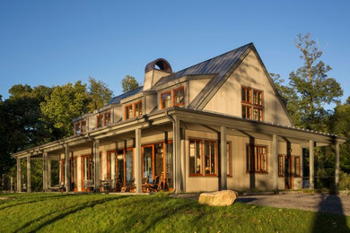 Immagine della villa grande beige classica a tre piani con rivestimento in legno, tetto a capanna e copertura in metallo o lamiera