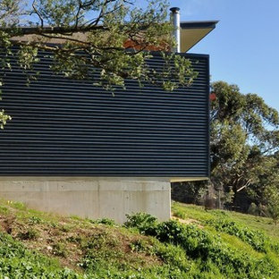 Ejemplo de fachada azul, contemporánea, de tamaño medio, de una planta, con revestimiento de metal y tejado plano
