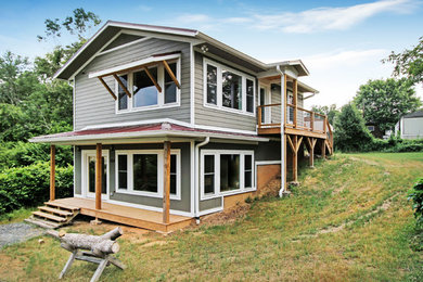 Imagen de fachada de casa gris actual de tamaño medio de dos plantas con revestimiento de vinilo, tejado a dos aguas y techo verde