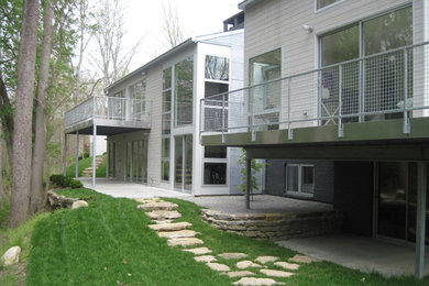 Ejemplo de fachada gris actual de tamaño medio a niveles con revestimiento de madera y tejado a cuatro aguas