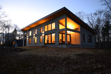 Photo of a medium sized and gey contemporary bungalow house exterior in Boston with wood cladding.