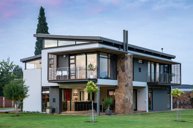 Diseño de fachada de casa blanca actual grande de dos plantas con revestimientos combinados y tejado de metal