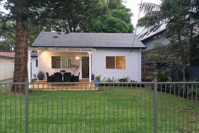 Photo of a medium sized and gey modern bungalow house exterior in Sydney with wood cladding and a pitched roof.