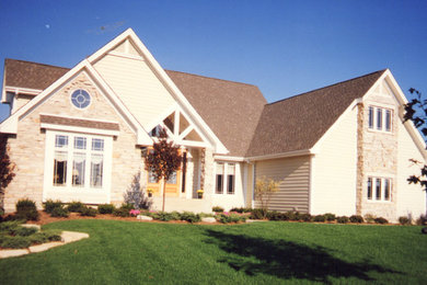 Photo of a beige contemporary bungalow house exterior in Chicago with a pitched roof.