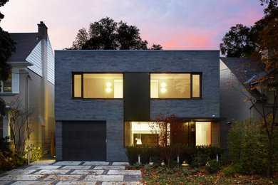 This is an example of a gey and medium sized modern two floor brick detached house in Toronto with a flat roof.