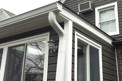 Ejemplo de fachada de casa gris tradicional de tamaño medio de dos plantas con revestimiento de vinilo, tejado a dos aguas y tejado de teja de madera