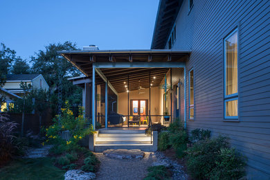 Imagen de fachada de casa gris contemporánea de tamaño medio de dos plantas con revestimiento de madera, tejado a dos aguas y tejado de metal