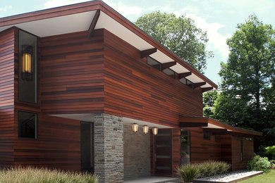 Modelo de fachada marrón actual grande de dos plantas con revestimiento de madera y tejado plano