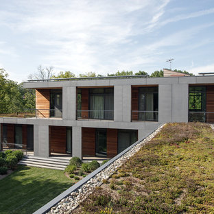 Modelo de fachada de casa gris, minimalista, grande, de dos plantas, con revestimiento de hormigón, tejado plano y techo verde