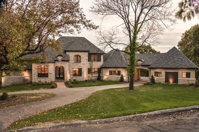 Large rustic beige two-story stone gable roof idea in St Louis