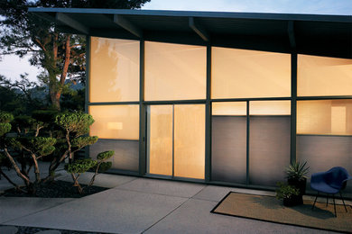 Esempio della facciata di una casa grigia moderna a un piano di medie dimensioni con rivestimento in vetro e tetto piano