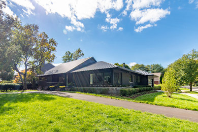Cette photo montre une façade de maison grise moderne de taille moyenne et de plain-pied avec un toit à quatre pans et un toit en métal.