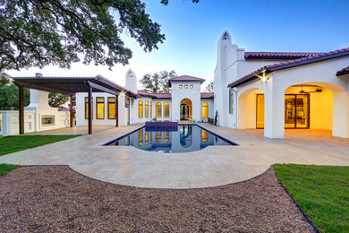 Example of a huge transitional white one-story adobe house exterior design in Austin with a hip roof and a tile roof