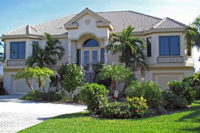 Inspiration for a large mediterranean white two-story stucco house exterior remodel in Tampa with a hip roof and a tile roof
