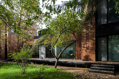 Imagen de fachada de casa marrón urbana de tamaño medio de dos plantas con revestimiento de madera y tejado plano