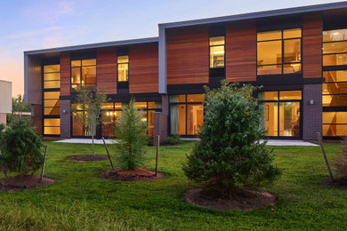 Imagen de fachada de casa pareada marrón y gris minimalista de tamaño medio de dos plantas con revestimiento de madera, tejado plano, tejado de varios materiales y tablilla