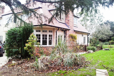 This is an example of a large and beige contemporary two floor brick detached house in Other with a hip roof and a tiled roof.