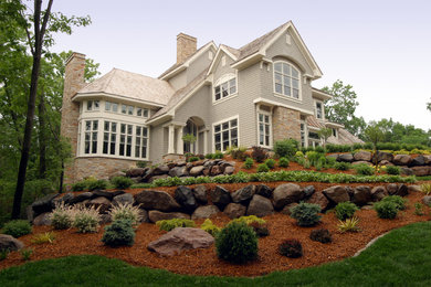 Large arts and crafts gray three-story stone exterior home photo in Minneapolis with a hip roof