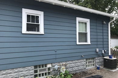 Diseño de fachada de casa azul de estilo americano de tamaño medio de una planta con revestimiento de madera, tejado a dos aguas y tejado de teja de madera