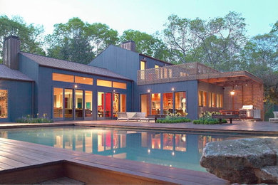 Diseño de fachada de casa verde contemporánea grande de dos plantas con revestimiento de madera, tejado a dos aguas y tejado de teja de barro