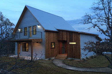 Ejemplo de fachada de casa gris campestre de tamaño medio de dos plantas con revestimiento de metal, tejado de un solo tendido y tejado de metal