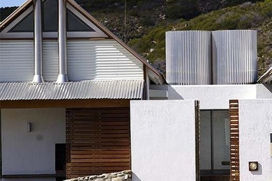 Diseño de fachada de casa blanca marinera de tamaño medio de una planta con revestimiento de metal, tejado de un solo tendido y tejado de metal