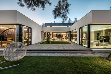 Diseño de fachada de casa blanca contemporánea grande de una planta con revestimientos combinados, tejado plano y tejado de varios materiales