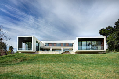 Modelo de fachada blanca minimalista grande de dos plantas con tejado plano, revestimiento de vidrio y escaleras