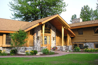 Bild på ett stort rustikt brunt hus, med allt i ett plan, valmat tak och tak i shingel