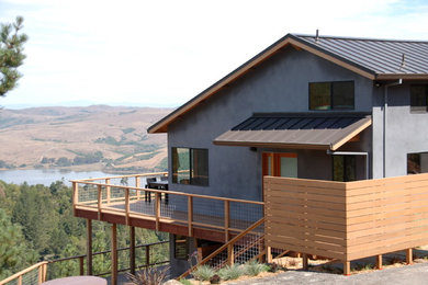 Diseño de fachada de casa gris contemporánea grande de dos plantas con revestimiento de hormigón, tejado a dos aguas y tejado de metal