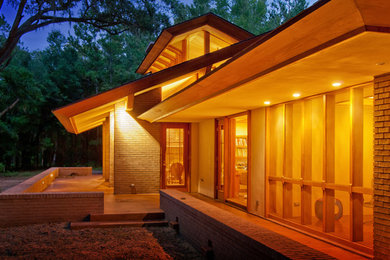 Imagen de fachada de casa beige contemporánea grande de una planta con revestimientos combinados y tejado a dos aguas