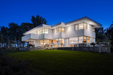 На фото: большой, двухэтажный, серый частный загородный дом в современном стиле с облицовкой из цементной штукатурки и плоской крышей