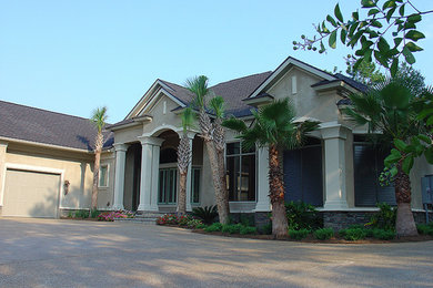 Example of a large classic beige two-story stucco house exterior design in Miami with a clipped gable roof and a shingle roof
