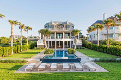 This is an example of an expansive and brown coastal house exterior in Charleston with three floors and a hip roof.