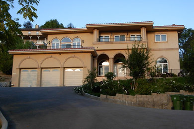 Foto de fachada de casa beige mediterránea grande de dos plantas con tejado plano, revestimiento de estuco y tejado de teja de madera