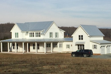 Foto de fachada de casa campestre de dos plantas con revestimiento de aglomerado de cemento, tejado a dos aguas y tejado de metal